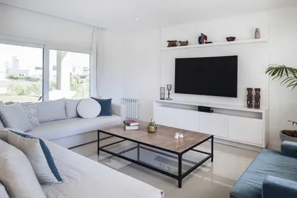 Living moderno minimalista con TV, sofá azul y piso blanco — proyecto TRV 137, por Estudio Arq Daniel Tarrio