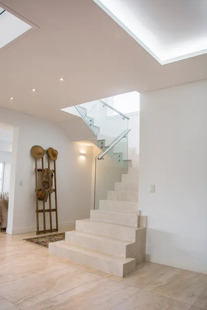 Escalera de hormigón con barandal vidrio y doble altura iluminada — proyecto TRV 620, por Estudio Arq Daniel Tarrio