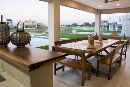 Comedor moderno con mesa de madera y vista a pileta y jardín — proyecto TRV 620, por Estudio Arq Daniel Tarrio