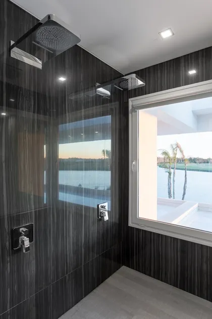 Baño contemporáneo con ducha abierta y vista a lago — proyecto TRV 490, por Estudio Arq Daniel Tarrio