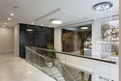 Pasillo moderno con escalera de vidrio y doble altura luminoso — proyecto TRV 490, por Estudio Arq Daniel Tarrio