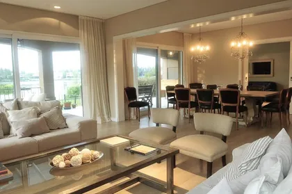 Living contemporáneo con ventanales, muebles beige y vista panorámica — proyecto Altamira del Lago, por Marconi Silva Arquitectos, en Tigre