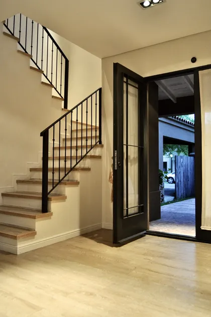 Escalera negra con peldaños de madera, entrada vidriada a exterior — proyecto Altamira del Lago, por Marconi Silva Arquitectos, en Tigre