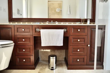 Baño con mesada de madera oscura y espejo grande decorativo — proyecto Ayres del Pilar, por Marconi Silva Arquitectos, en Pilar
