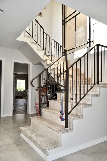 Escalera moderna con barandas de hierro negro y peldaños en madera clara — proyecto Buenos Aires Village, por Marconi Silva Arquitectos, en Bella Vista