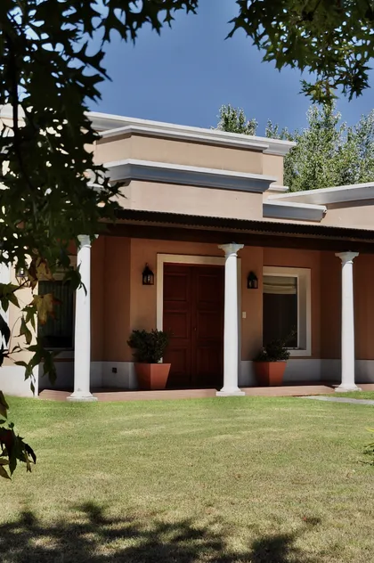 Casa contemporánea con fachada terracota, columnas blancas y patio — proyecto Chacras de la Cruz, por Marconi Silva Arquitectos, en Capilla del Señor