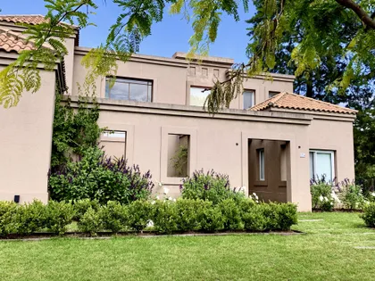 Casa contemporánea beige con fachada abierta y jardín verde frontal — proyecto El Encuentro , por Marconi Silva Arquitectos, en Benavidez