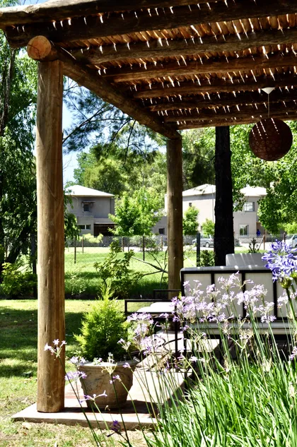 Pergola rustica de madera con jardin florecido y vista al verde — proyecto El Encuentro  2, por Marconi Silva Arquitectos, en Benavidez