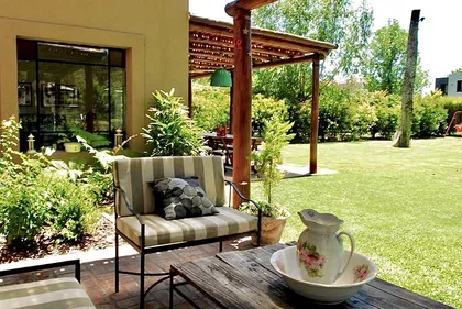 Patio con sillón, pergola de madera y jardin amplio al fondo — proyecto El Encuentro  2, por Marconi Silva Arquitectos, en Benavidez