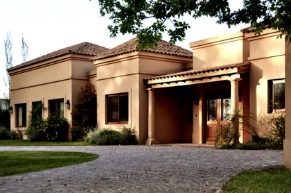 Casa moderna terracota con pergola y jardín al atardecer — proyecto El Solar de Capilla, por Marconi Silva Arquitectos, en Capilla del Señor
