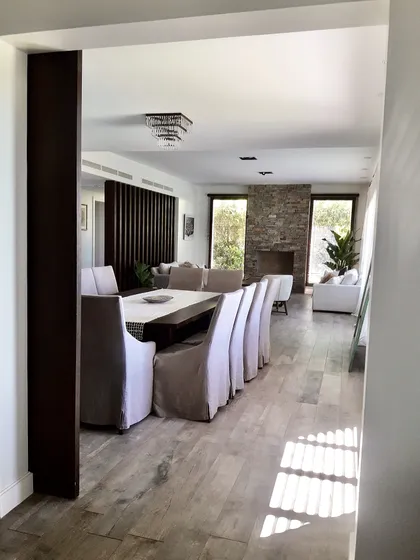 Comedor moderno con mesa negra, sillas tapizadas blancas, pared ladrillo — proyecto Golf Club Nordelta, por Marconi Silva Arquitectos, en Nordelta