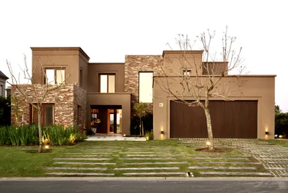 Casa contemporánea con fachada de ladrillo y piedra, patio verde — proyecto Golf Club Nordelta, por Marconi Silva Arquitectos, en Nordelta