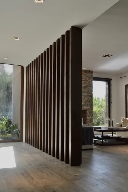 Tabique divisor en listones de madera negra en vivienda moderna — proyecto Golf Club Nordelta, por Marconi Silva Arquitectos, en Nordelta
