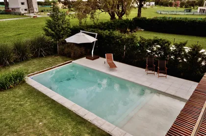 Pileta rectangular con deck de madera en jardín verde privado — proyecto Haras Santa María, por Marconi Silva Arquitectos, en Escobar