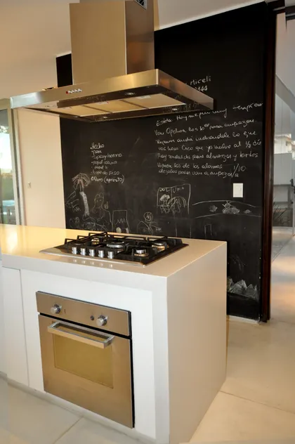 Cocina moderna con isla, plancha integrada y pizarra negra de fondo — proyecto Haras Santa María, por Marconi Silva Arquitectos, en Escobar