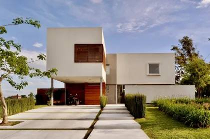 Casa contemporánea blanca con fachada geométrica y jardinería moderna — proyecto Haras Santa María, por Marconi Silva Arquitectos, en Escobar