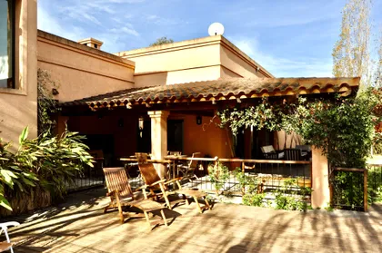 Patio con pérgola de madera, sillones y plantas trepadoras al atardecer — proyecto La Retama, por Marconi Silva Arquitectos, en Manzanares