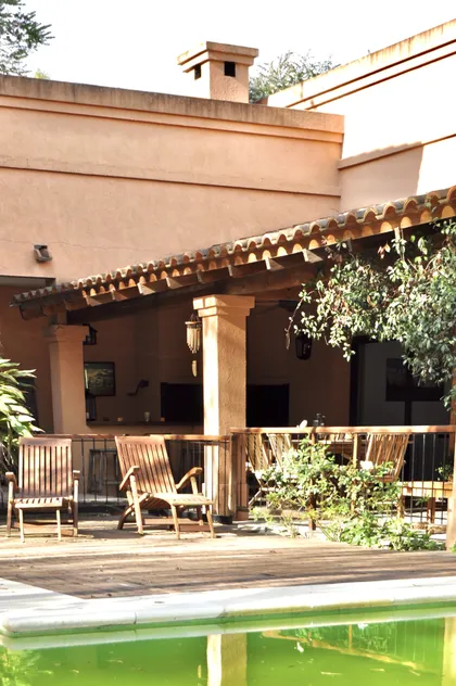 Patio con pileta verde, pergola madera y deck frente a casa terracota — proyecto La Retama, por Marconi Silva Arquitectos, en Manzanares