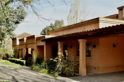 Casa de estilo mediterráneo con fachada terracota y galería cubierta — proyecto La Retama, por Marconi Silva Arquitectos, en Manzanares