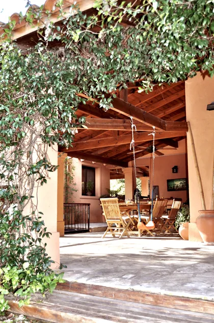 Patio cubierto con pérgola de madera y enredaderas naturales — proyecto La Retama, por Marconi Silva Arquitectos, en Manzanares