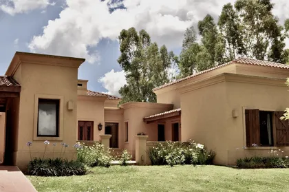 Casa beige de arquitectura contemporanea con jardin y arboles altos — proyecto La Retama 2, por Marconi Silva Arquitectos, en Manzanares