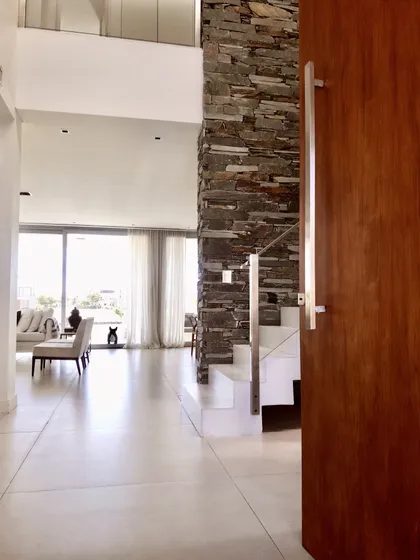 Pasillo moderno con ladrillo visto y puerta de madera caoba — proyecto Lagos del Golf, por Marconi Silva Arquitectos, en Nordelta