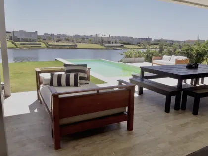 Terraza con pileta verde, deck de madera y mobiliario contemporáneo — proyecto Lagos del Golf, por Marconi Silva Arquitectos, en Nordelta