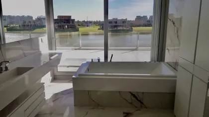 Baño moderno con bañera de mármol y vista al río — proyecto Lagos del Golf, por Marconi Silva Arquitectos, en Nordelta