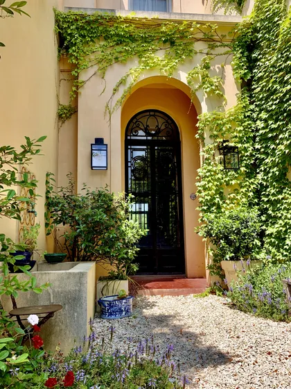 Entrada con arco terracota, puerta negra y enredaderas verdes — proyecto Lagos del Norte, por Marconi Silva Arquitectos, en Don Torcuato