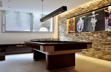 Showroom moderno con pared de ladrillo visto iluminada y muebles negros — proyecto Martindale Country Club, por Marconi Silva Arquitectos, en Pilar