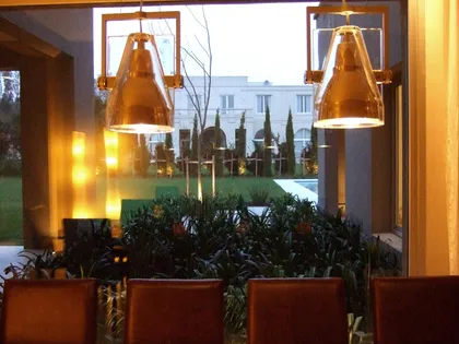 Balcón con lámparas colgantes doradas y plantas en macetas terracota — proyecto Martindale Country Club, por Marconi Silva Arquitectos, en Pilar