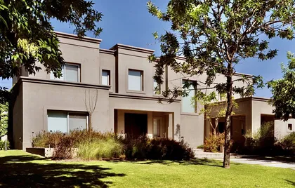 Casa contemporánea beige con jardín, árboles y fachada minimalista — proyecto Martindale Country Club, por Marconi Silva Arquitectos, en Pilar