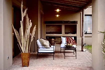 Galeria exterior con sillones, hogar, techo madera y luminaria cálida — proyecto Talar del Lago 2, por Marconi Silva Arquitectos, en Pacheco