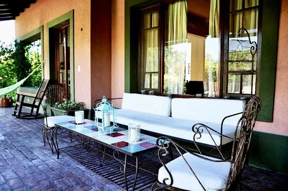 Galería cubierta con sillón y mesa ratona, vista a jardín — proyecto Valle Claro, por Marconi Silva Arquitectos, en Benavidez