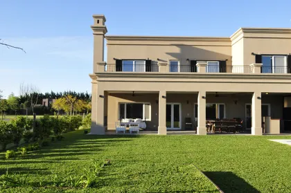 Casa moderna beige con ventanales grandes y jardín de pasto verde — proyecto TDL 353, por Estudio Arq Daniel Tarrio