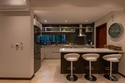 Cocina moderna abierta con isla y barra, gabinetes de madera — proyecto Costa Esmeralda 1, por Arquitecto Caceres, en Costa Esmeralda