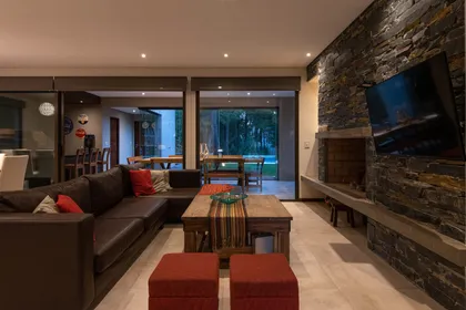 Living comedor moderno con pared de piedra y sillón de cuero — proyecto Costa Esmeralda 1, por Arquitecto Caceres, en Costa Esmeralda