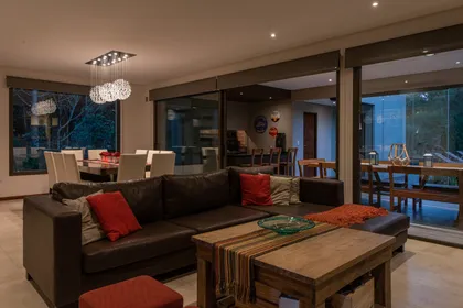 Living comedor moderno con ventanales y sofá grande negro — proyecto Costa Esmeralda 1, por Arquitecto Caceres, en Costa Esmeralda