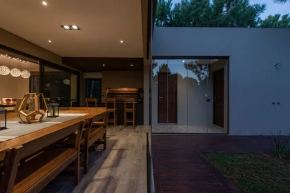 Comedor exterior moderno con deck, parrilla y luces cálidas — proyecto Costa Esmeralda 1, por Arquitecto Caceres, en Costa Esmeralda