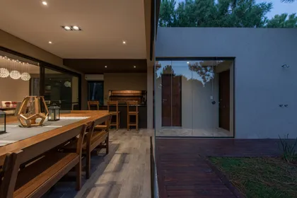 Comedor exterior moderno con deck de madera y ventanales amplios — proyecto Costa Esmeralda 1, por Arquitecto Caceres, en Costa Esmeralda