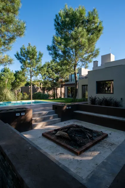 Patio moderno con piscina, hogar a leña y arquitectura brutalista — proyecto Costa Esmeralda 1, por Arquitecto Caceres, en Costa Esmeralda