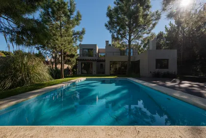 Piscina moderna rodeada de jardín y casa contemporánea — proyecto Costa Esmeralda 1, por Arquitecto Caceres, en Costa Esmeralda