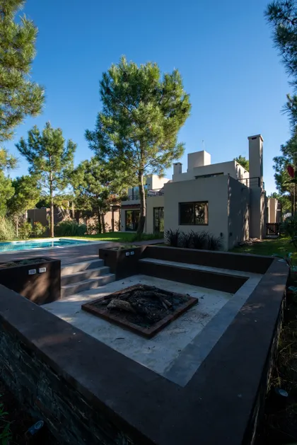 piscina moderna con fogonero y estar exterior integrado — proyecto Costa Esmeralda 1, por Arquitecto Caceres, en Costa Esmeralda
