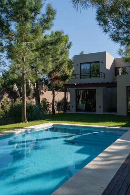 Casa moderna con piscina y árboles en entorno suburbano — proyecto Costa Esmeralda 1, por Arquitecto Caceres, en Costa Esmeralda