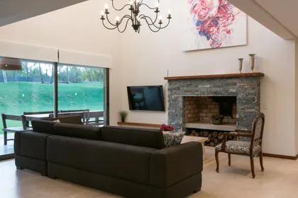 Living amplio con doble altura, chimenea y ventanales al campo — proyecto Costa Esmeralda 2, por Arquitecto Caceres, en Costa Esmeralda