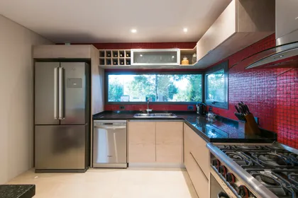 Cocina moderna con azulejos rojos y vista al bosque — proyecto Costa Esmeralda 2, por Arquitecto Caceres, en Costa Esmeralda