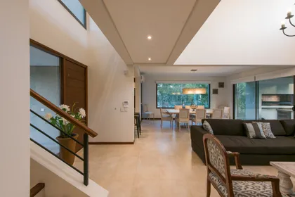 Living moderno con doble altura y escalera flotante — proyecto Costa Esmeralda 2, por Arquitecto Caceres, en Costa Esmeralda