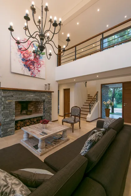 Living moderno con chimenea de piedra y doble altura — proyecto Costa Esmeralda 2, por Arquitecto Caceres, en Costa Esmeralda