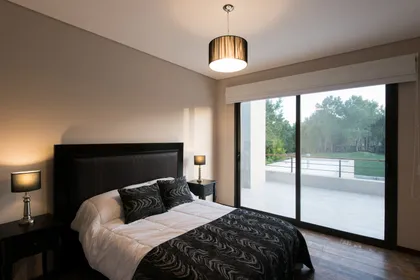 Dormitorio moderno con cama amplia, luces indirectas y ventana al exterior — proyecto Costa Esmeralda 2, por Arquitecto Caceres, en Costa Esmeralda