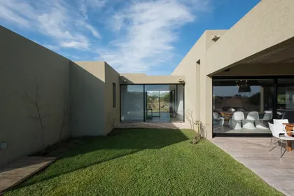 Casa moderna en L con patio interior y deck de madera — proyecto Costa Esmeralda 3, por Arquitecto Caceres, en Costa Esmeralda